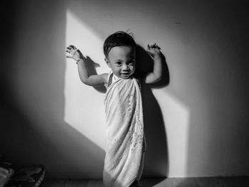 Cute girl standing against wall at home