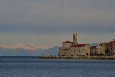 Sea by buildings against sky in city