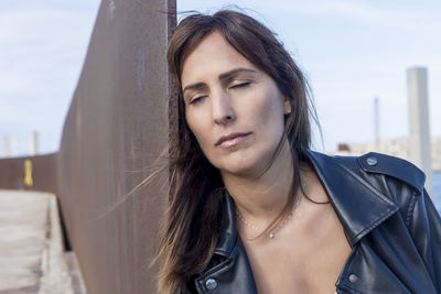 Mature woman leaning on railing against sky