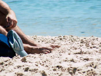 Low section of man sitting at beach