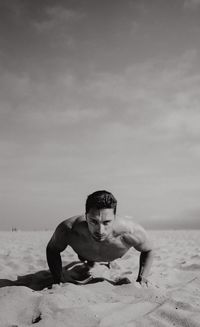 Portrait of shirtless man exercising at beach