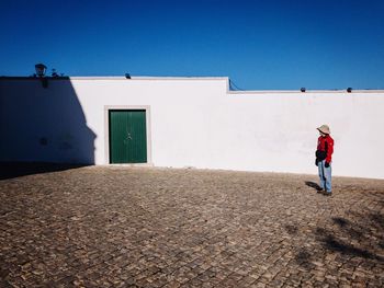 Full length of woman standing by building during sunny day