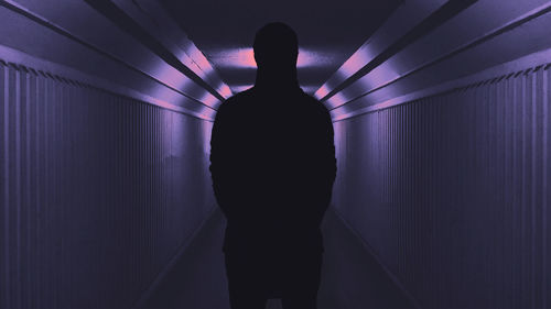 Silhouette of a man in the hallway, back view, purple lighting