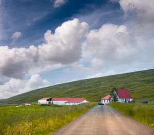 Road amidst field against sky