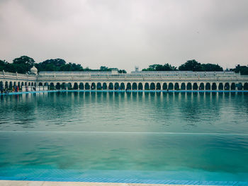 View of swimming pool by lake against sky