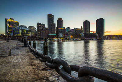 Scenic view of river by buildings against sky during sunset