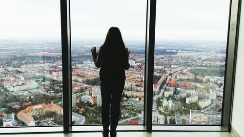 Rear view of girl standing against glass window