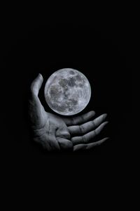 Human hand holding moon at night