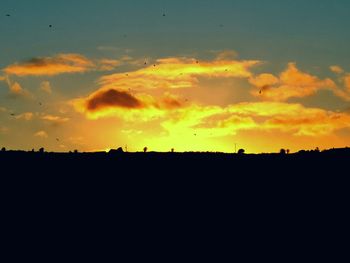 Silhouette landscape against dramatic sky during sunset