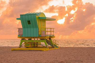 Lifeguard hut on beach against sky during sunset