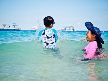 Boys swimming in sea against sky