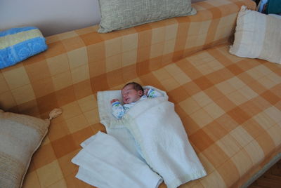 Close-up of cute baby lying on bed at home