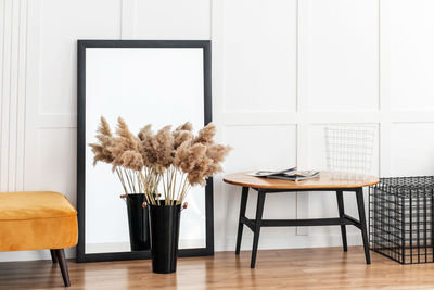 On the wooden floor there is an orange banquette, a large mirror and a wooden table.