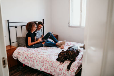 Young woman sitting on bed at home