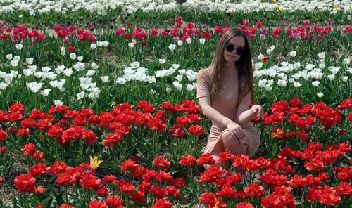 Woman with red flowers against plants