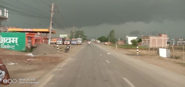 View of city street against cloudy sky