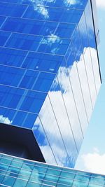 Low angle view of modern glass building against sky