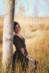 Young woman on tree trunk in field
