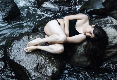 Full length of woman sleeping on rocks at beach