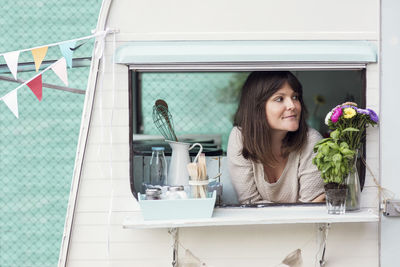 Thoughtful female owner looking out through food truck window