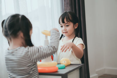 Sisters playing with multi colored toys at home