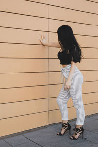 Side view of woman standing against wall