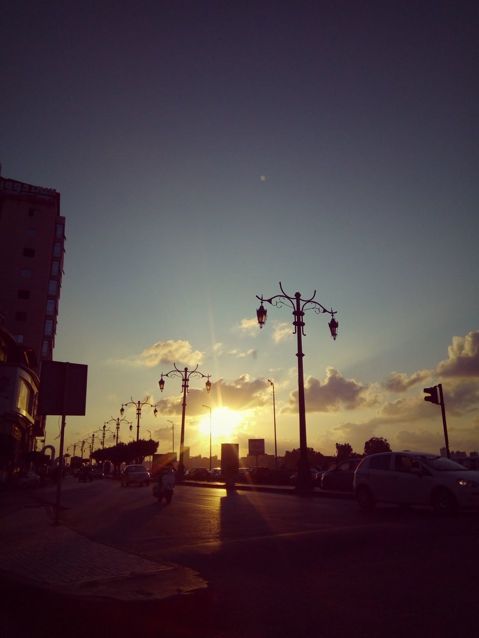 sky, evening, dusk, sunset, street, night, city, architecture, street light, nature, transportation, lighting, light, built structure, road, mode of transportation, car, building exterior, horizon, silhouette, no people, motor vehicle, afterglow, cloud, outdoors, darkness, city life, astronomical object