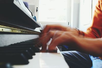 Cropped image of hand playing piano at home