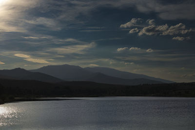 Scenic view of lake by mountains against sky