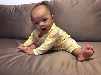 Cute baby girl lying on bed at home