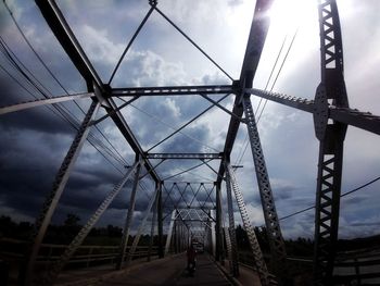 Rear view of woman walking on bridge against sky