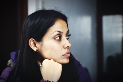 Thoughtful woman with hand on chin indoors