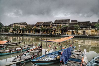 Fishing boats moored at harbor against sky