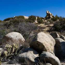 Scenic view of rocks on landscape against clear blue sky