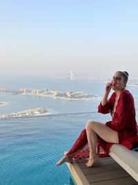 Side view of woman sitting by sea against sky dubai emirati arabi uniti emirates pool piscina 