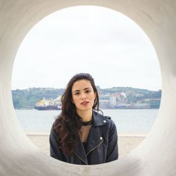 Portrait of woman seen through pipe against sky