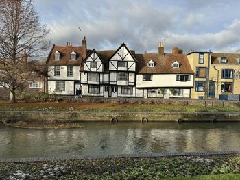 Houses by river against sky