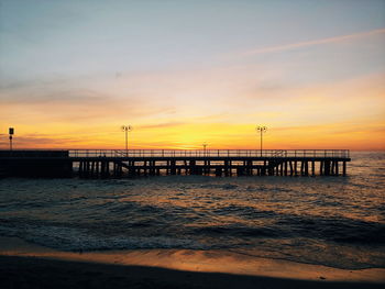 Pier over sea against sky during sunset