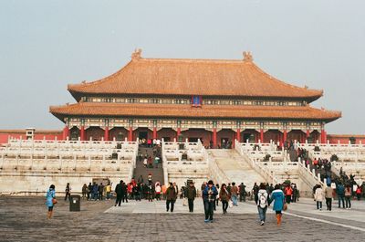 Group of people outside historic building against sky