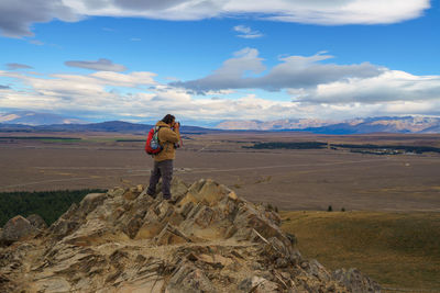 Man standing on mountain against cloudy sky