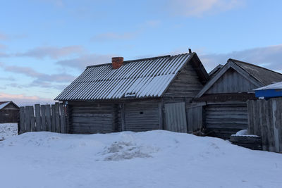 Houses on snow covered field against sky