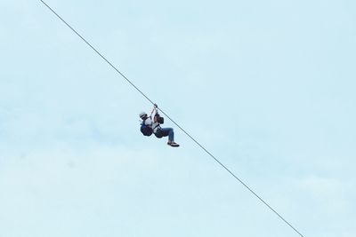 Low angle view of man on zip line against sky