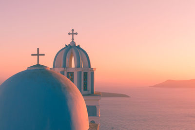 Church by sea against sky during sunset