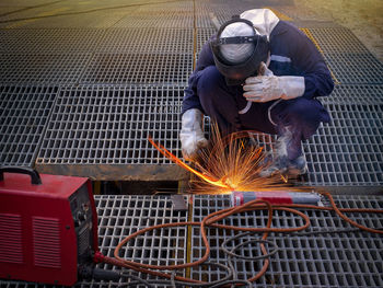 Worker welding metal in factory