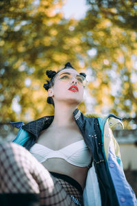 Low angle view of young woman sitting against trees