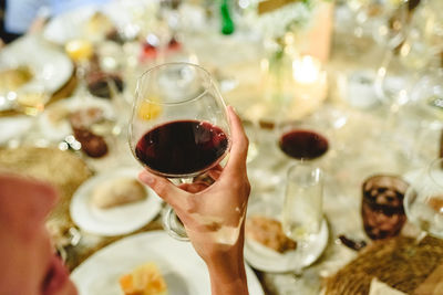 Close-up of hand holding wine glasses on table