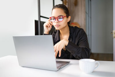 Portrait of young businesswoman using laptop on table