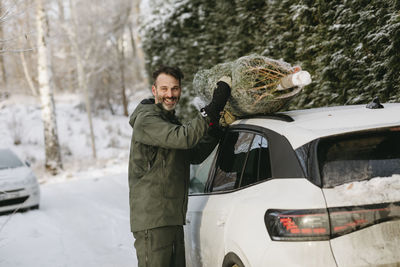 Man putting christmas tree on car roof