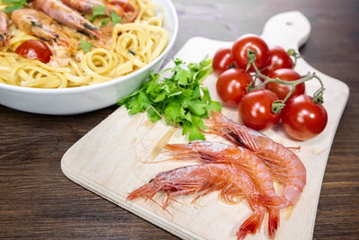 High angle view of pasta in plate by chopping board on table