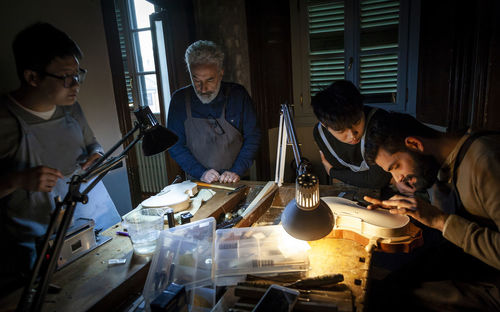 Group of craftsmen violin maker while working on a new violin in the workshop